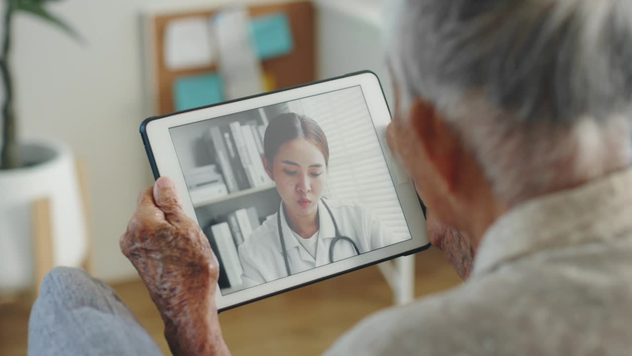 亚洲老年妇女灰白头发80-90年代视频电话与医生，远程医疗远程保健的概念视频素材