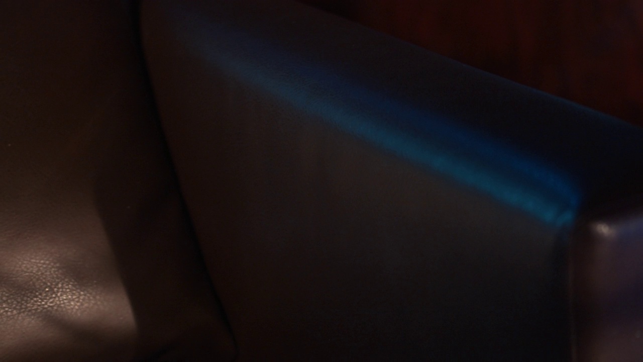 昏暗的客厅被蓝光照亮。看皮革椅子的细节视频素材