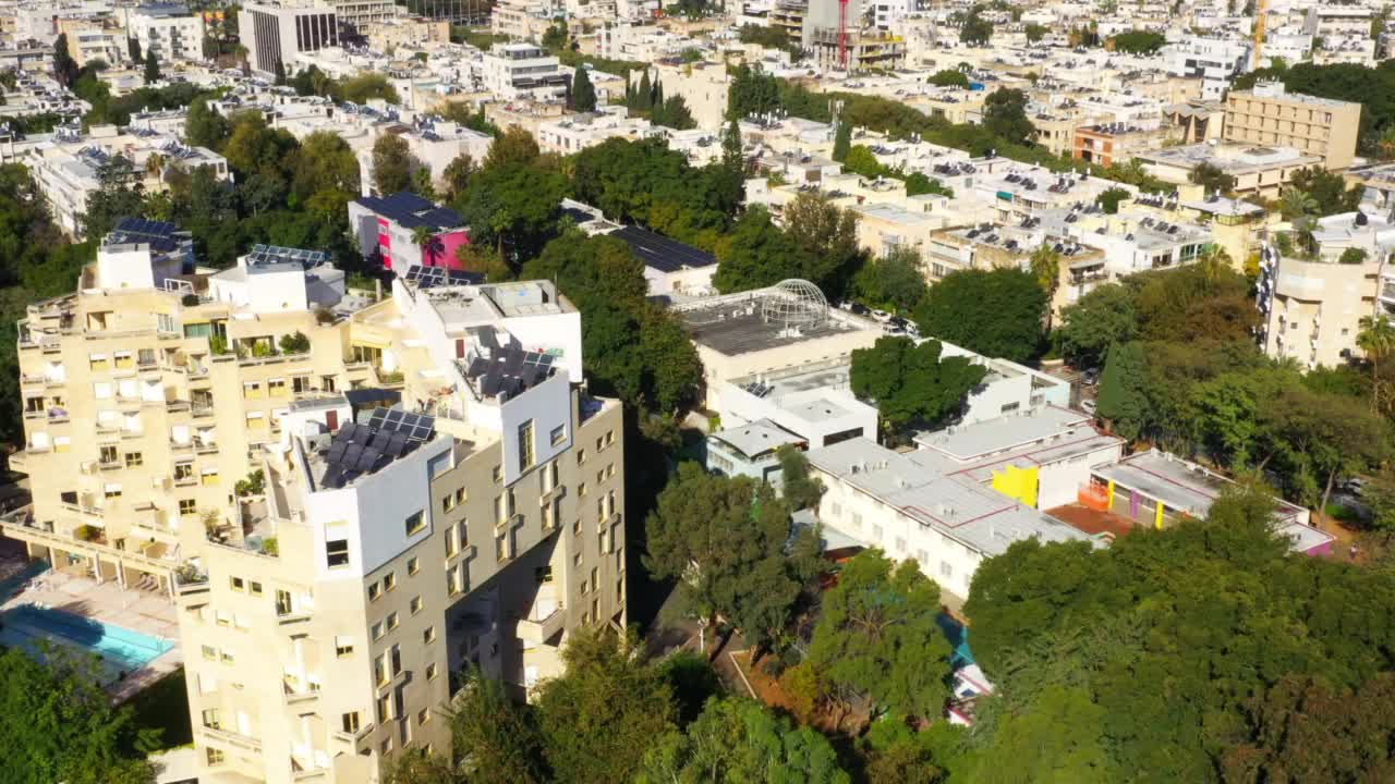 在阳光明媚的日子里，空中倾斜拍摄的绿树丛中的建筑物-特拉维夫，以色列视频素材