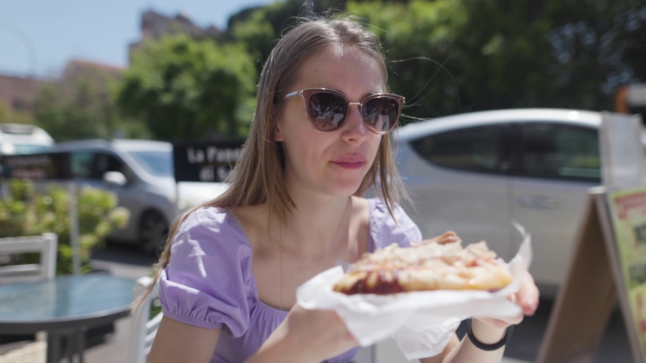 十几岁的女孩吃美味的西西里披萨在街头餐厅的桌子。视频素材