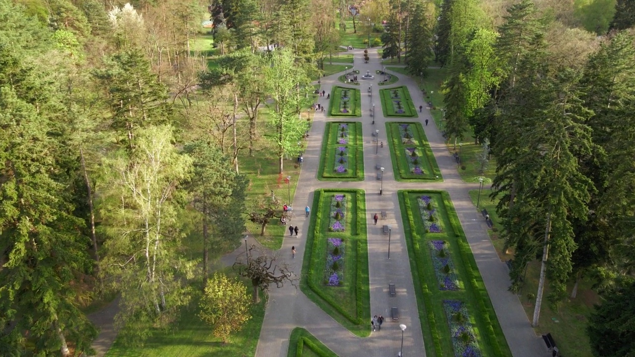 美丽优雅的公园花园鸟瞰壮举。装饰设计花坛和树木Vrnjacka Banja, Sebrbia 4K镜头。城市公园有绿色的树，花和草。视频下载