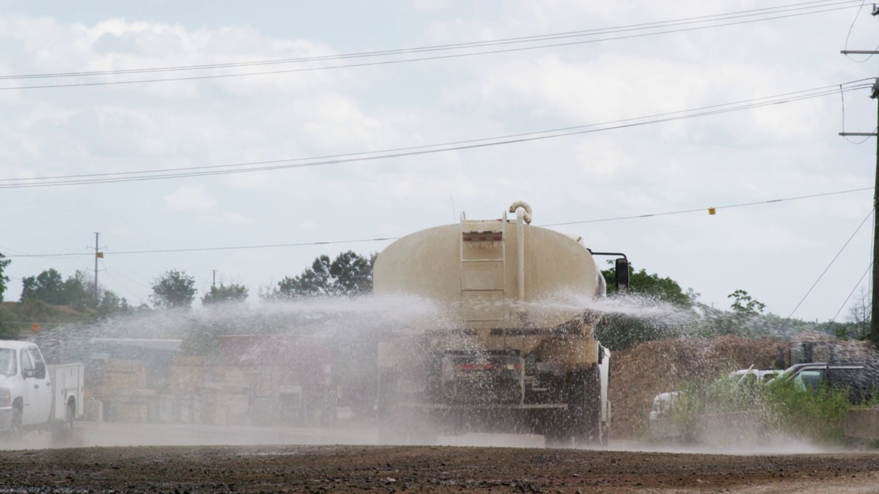 一辆水罐车在工地喷洒防尘喷雾的慢动作镜头视频下载