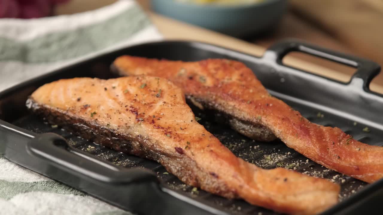 慢动作4k视频，烤烤三文鱼片放在黑色盘子上，撒上欧芹或莳萝。三文鱼是健康饮食和高蛋白饮食的食物视频下载