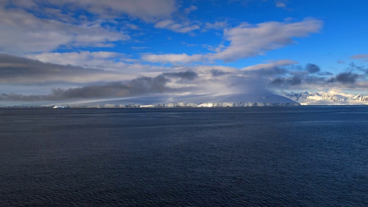 在多云的天空下积雪覆盖的山脉-南极半岛，南极洲视频素材