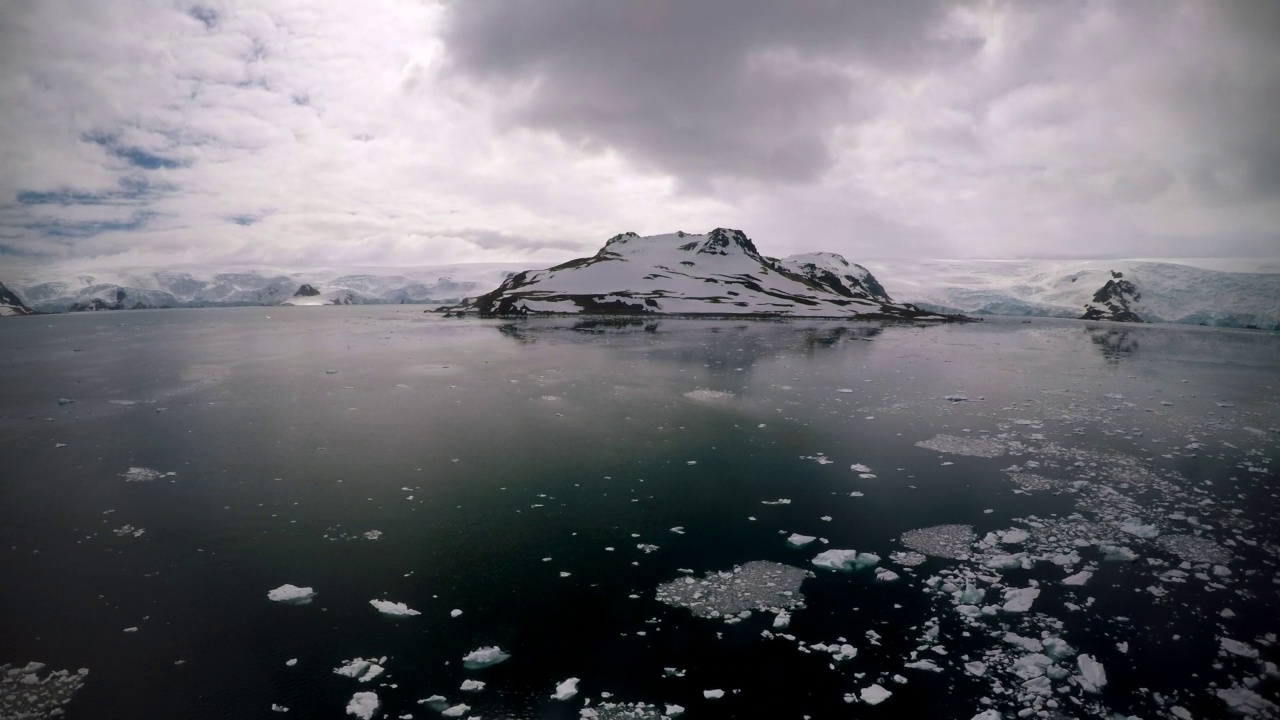 在多云的天空下，以冰山覆盖的海洋田诗般的雪山的观点拍摄-南极半岛，南极洲视频素材