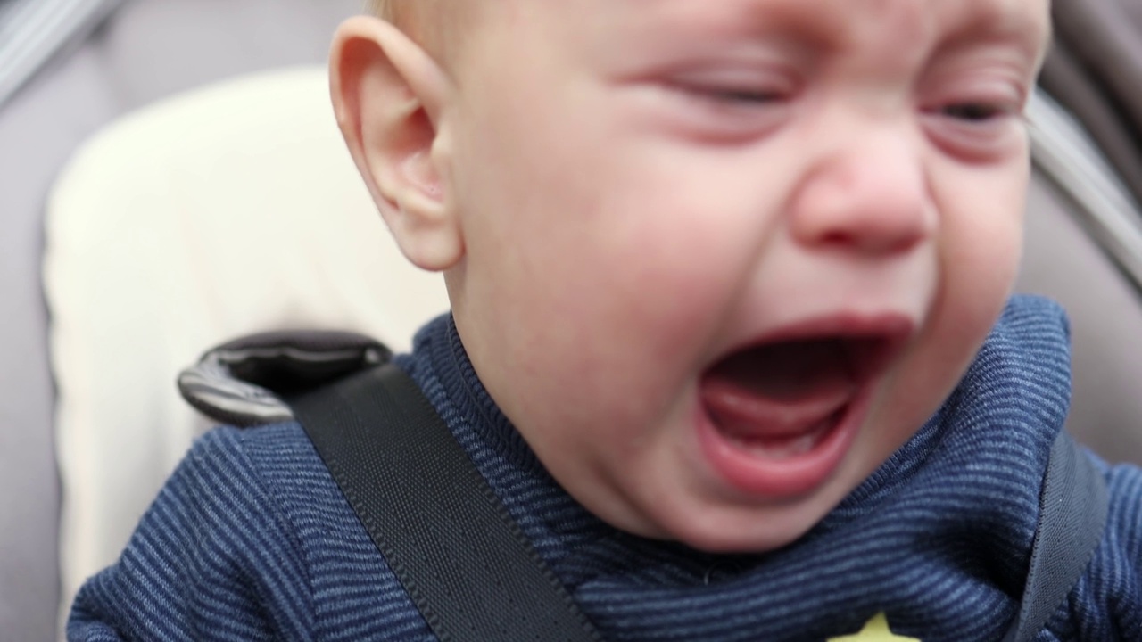 婴儿哭闹，婴儿画像，张开嘴牙齿，户外马车里挑剔的孩子视频素材