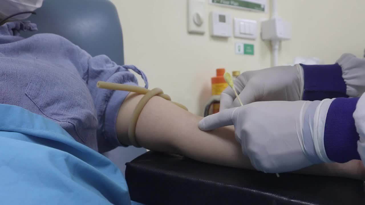 一名献血者的手臂，他正在进行献血，将针头插入手臂，并将血液放入与针头相连的管子中视频素材