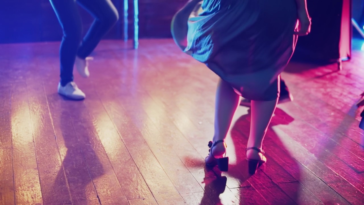 灯光下，男男女女的双腿在木地板上欢快地跳舞视频下载