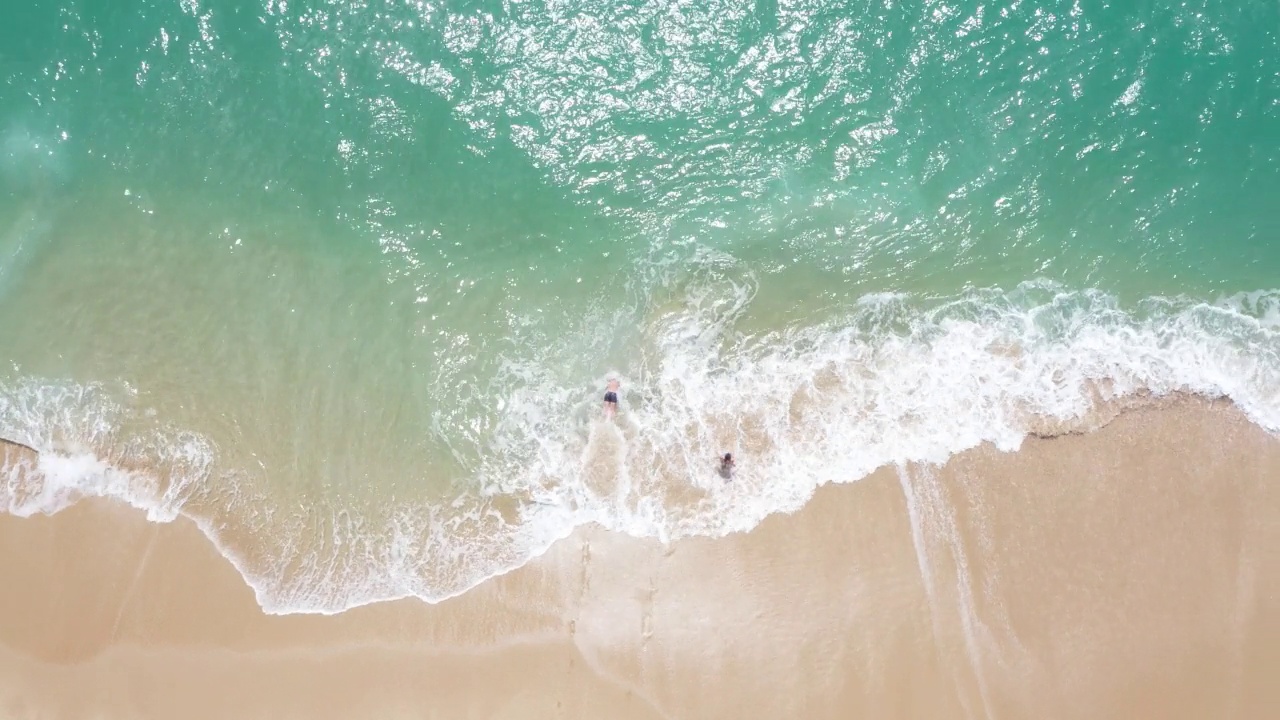 两个人沿着沙滩跑向浪花滔天的大海，然后潜入水中视频素材