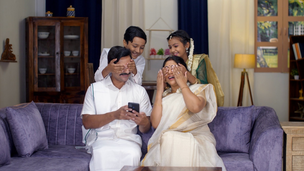 一个快乐的印度夫妻穿着民族服装，使用智能手机，对孩子、南印度家庭、传统服装感到惊讶视频素材