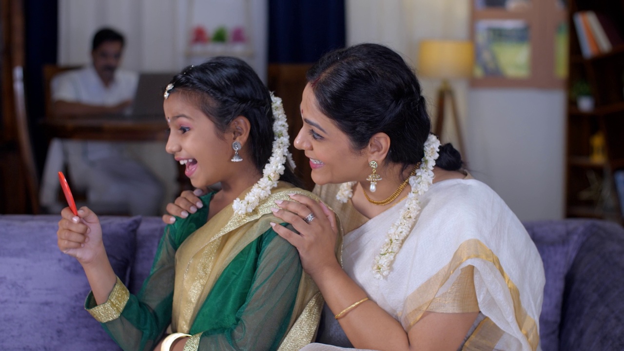 一位身着传统纱丽服的印度南部母亲将Gajra系在女儿的头发上——节日的感觉、养育、关怀和爱视频素材