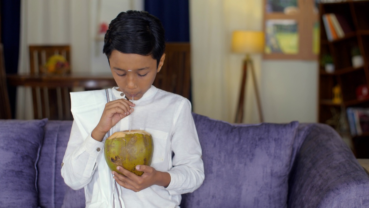 一个来自南印度的小男孩喝着鲜嫩的椰子水——夏日，营养丰富的食物视频素材