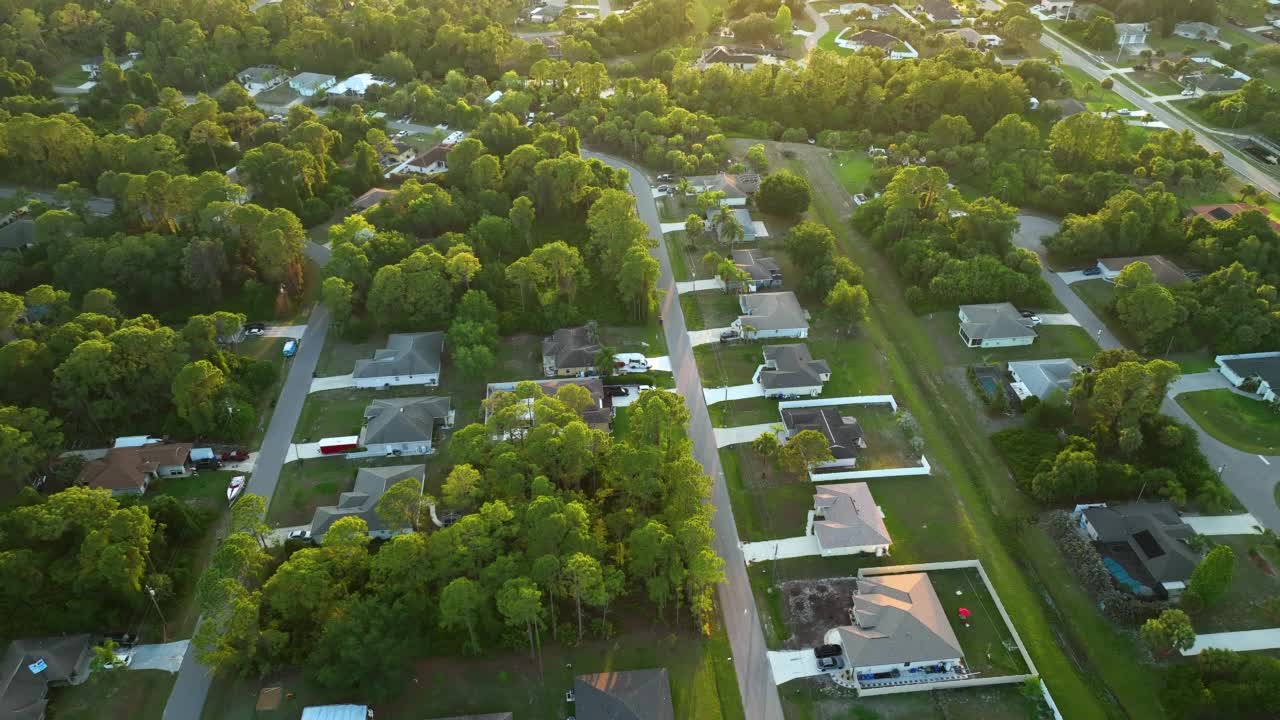 空中景观郊区私人住宅之间的绿色棕榈树在佛罗里达州宁静的农村地区在日落视频素材