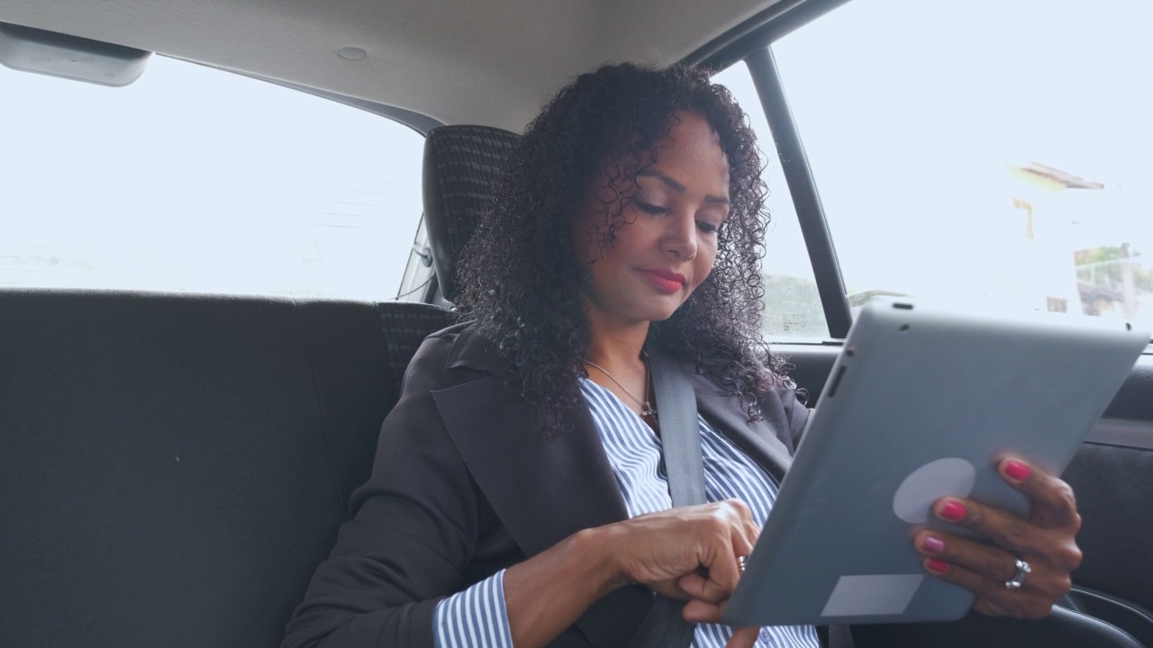 商务女性在使用私人交通工具的同时使用数字平板电脑视频素材