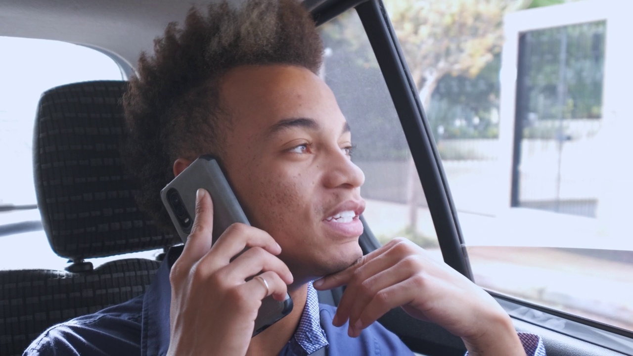 一位年轻的商人在一辆上下班的汽车的副驾驶座位上讲电话视频素材