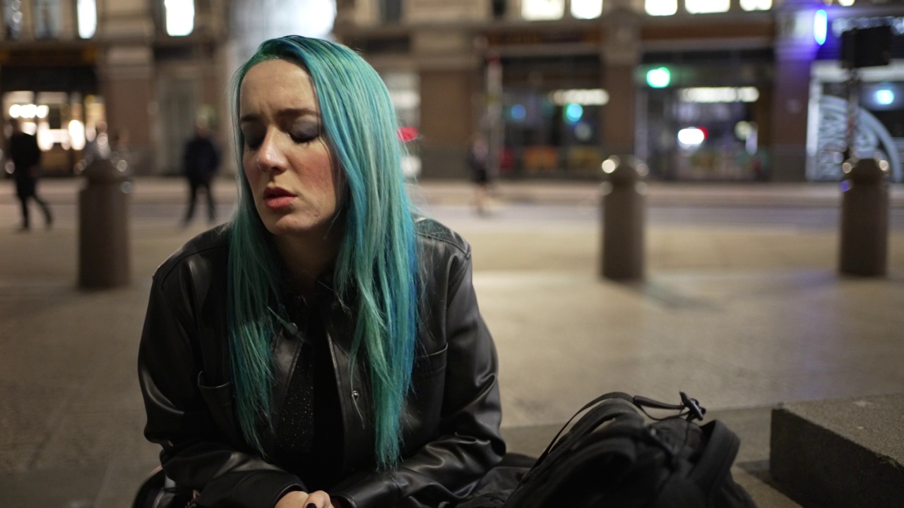 外面有一幅蓝色头发，情绪激动，正在哭泣的年轻女子的画像视频素材