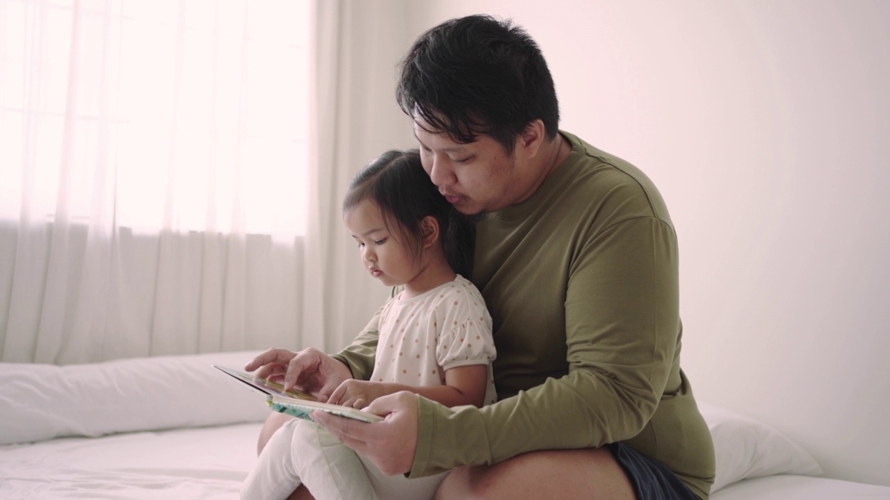 快乐的家庭时光，父亲在家教女儿读书视频素材