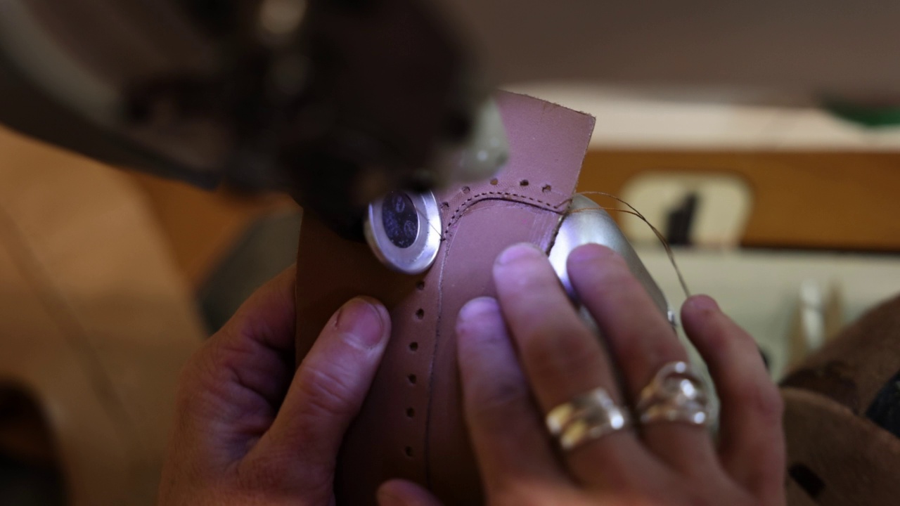 不知名的鞋匠，正在缝纫机上缝制鞋子的皮革部分视频素材