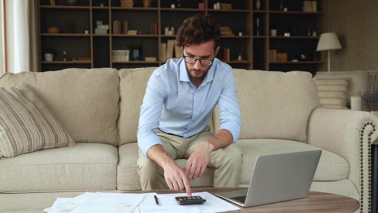 严肃的男人在家坐在沙发上做会计工作视频素材