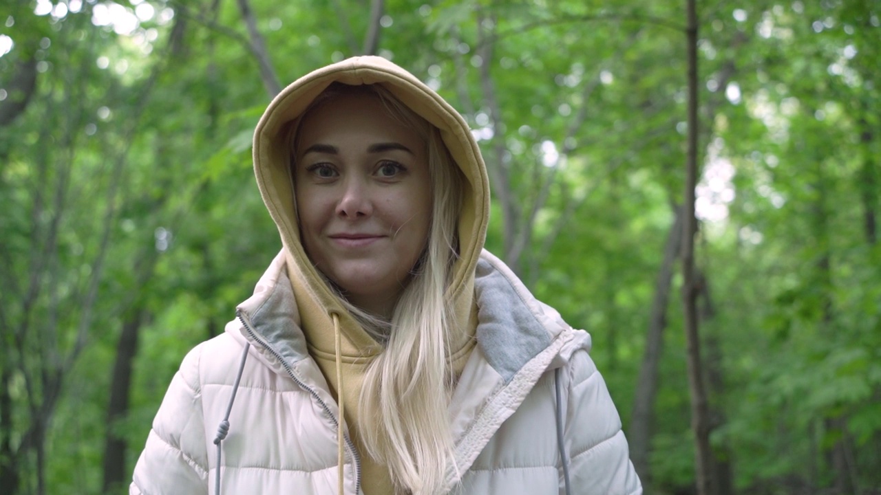 年轻迷人的高加索千禧一代女性看着镜头微笑在森林。视频素材
