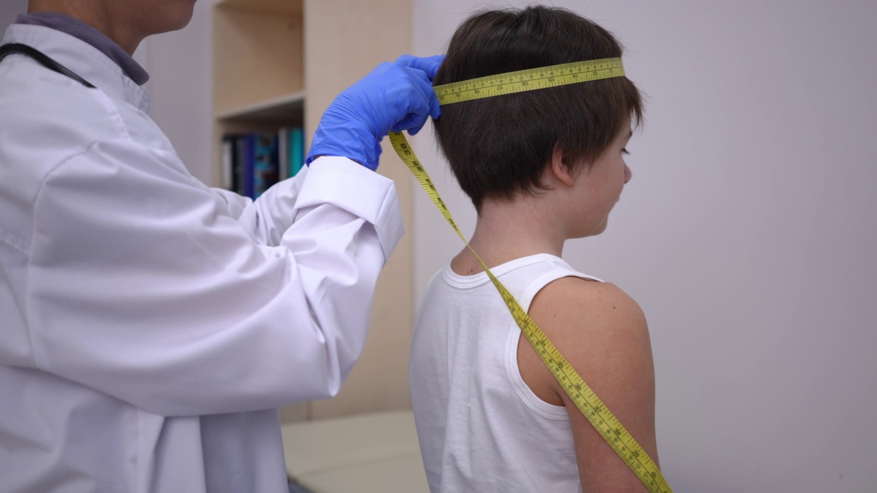 不知名的医生在医院测量白人男孩的肩膀和头部。集中专业儿科医生在医疗门诊室内采取儿童身体措施。视频下载