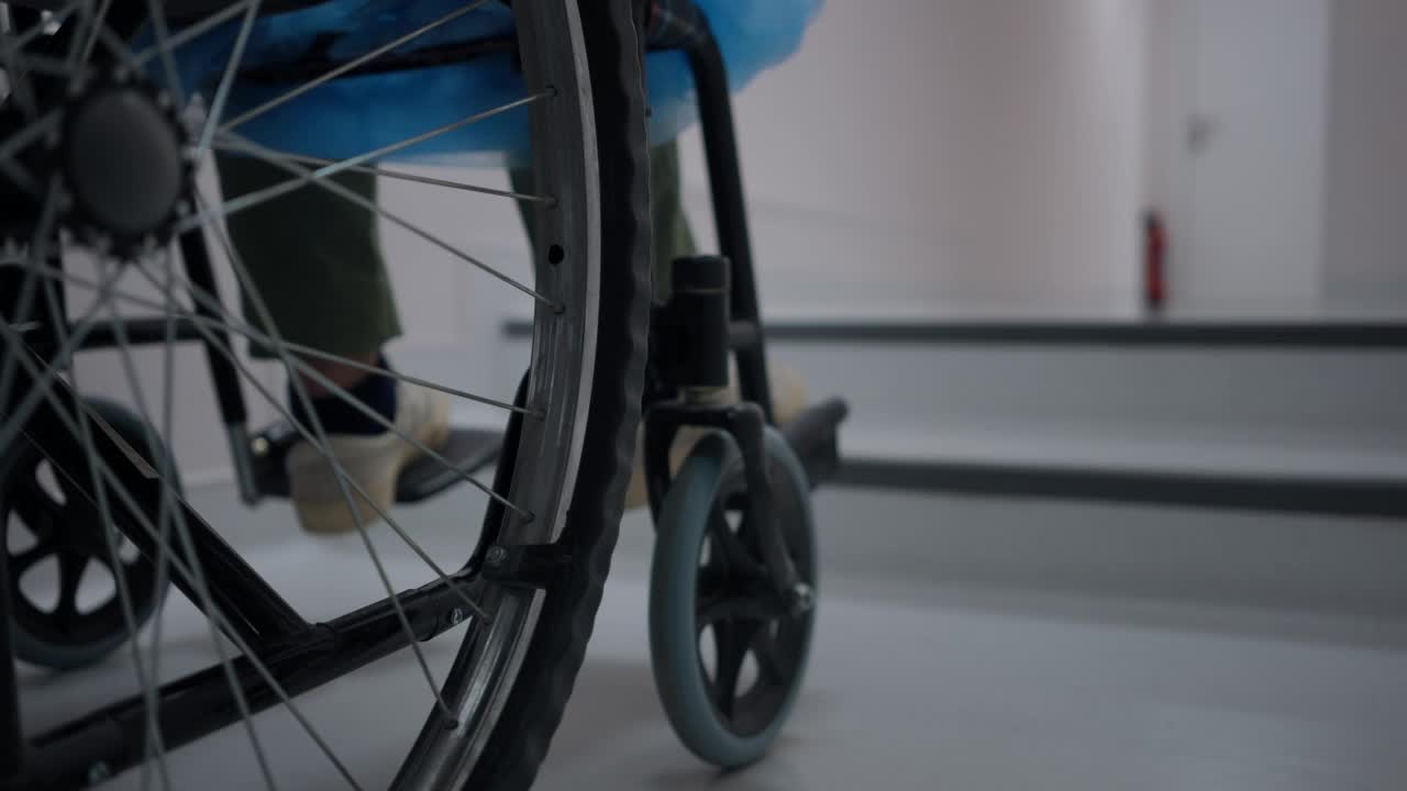 特写轮椅轮子在楼梯室内与认不出来的男孩。处所内的无障碍及残疾问题。视频素材