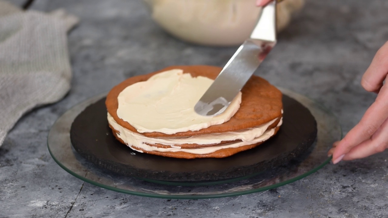 糕点师用锅铲在蛋糕层上抹上一层焦糖奶油。视频下载