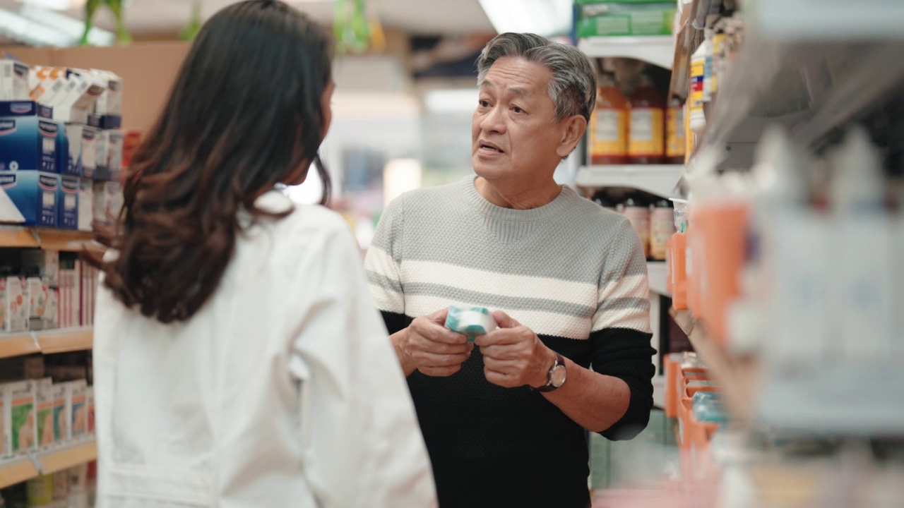 亚洲华裔女药剂师在药房走道向年长的男性顾客解释视频下载