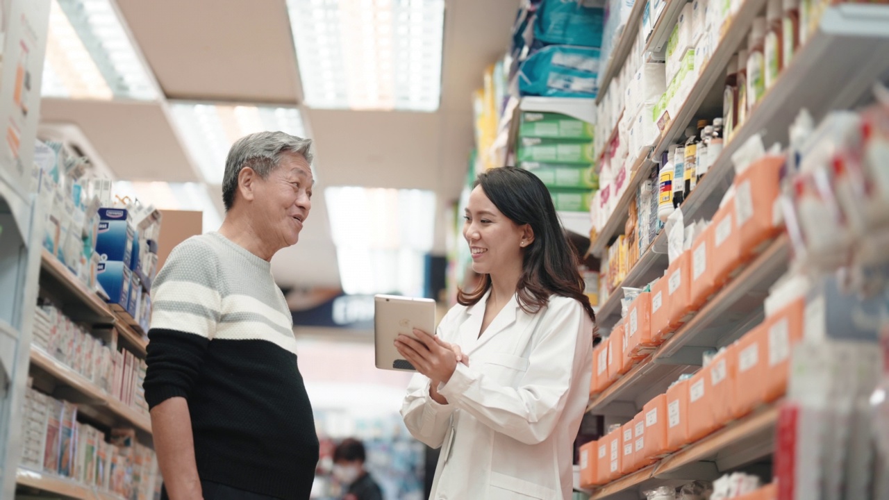亚洲华裔女药剂师在药房走道向年长的男性顾客解释视频下载