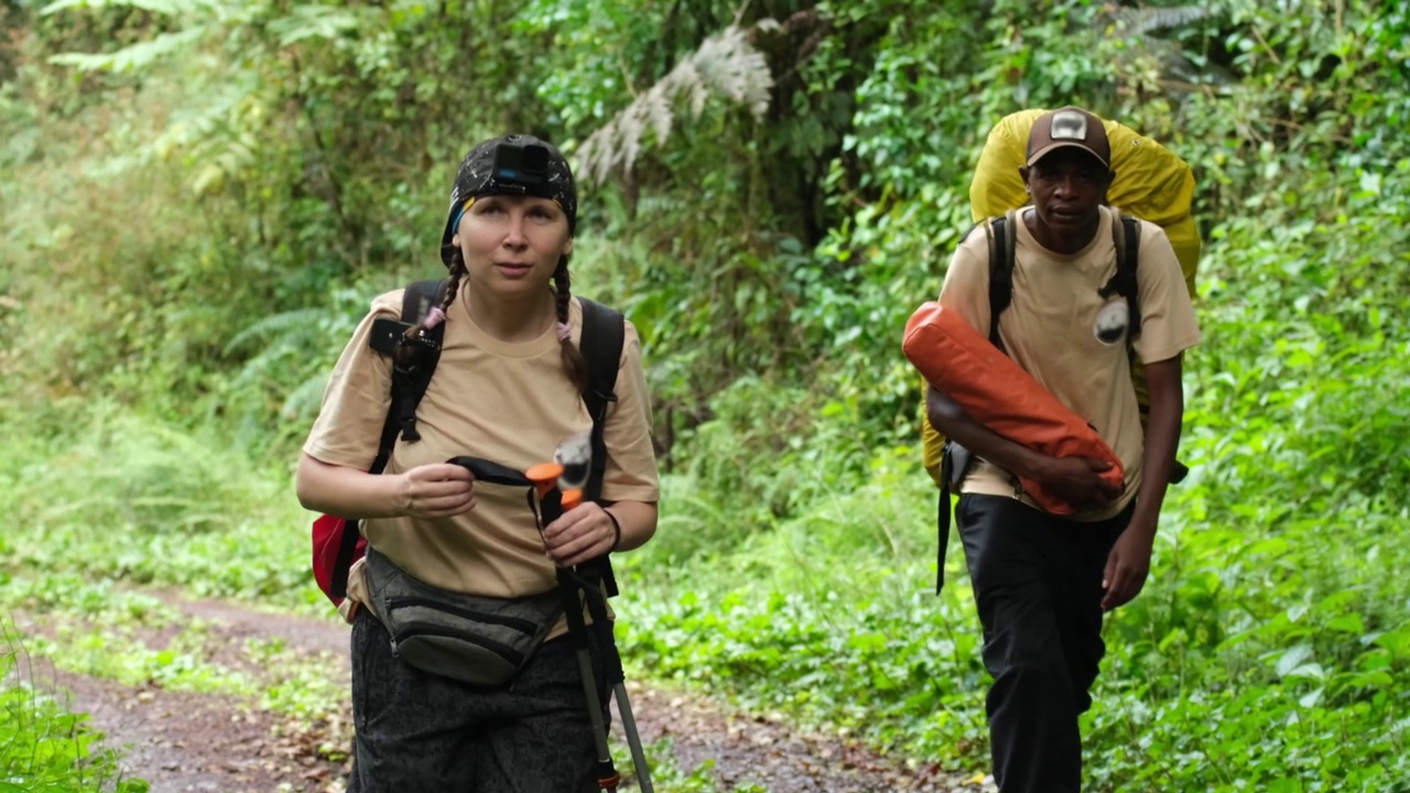 一个背着双肩包的女孩在向导的带领下徒步穿越雨林视频下载