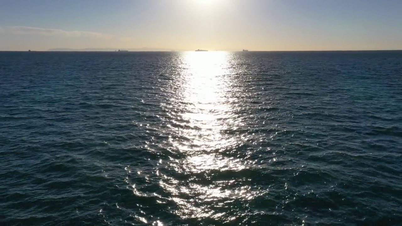 无人机在太平洋上空快速飞向地平线，太阳和船只在远处视频素材