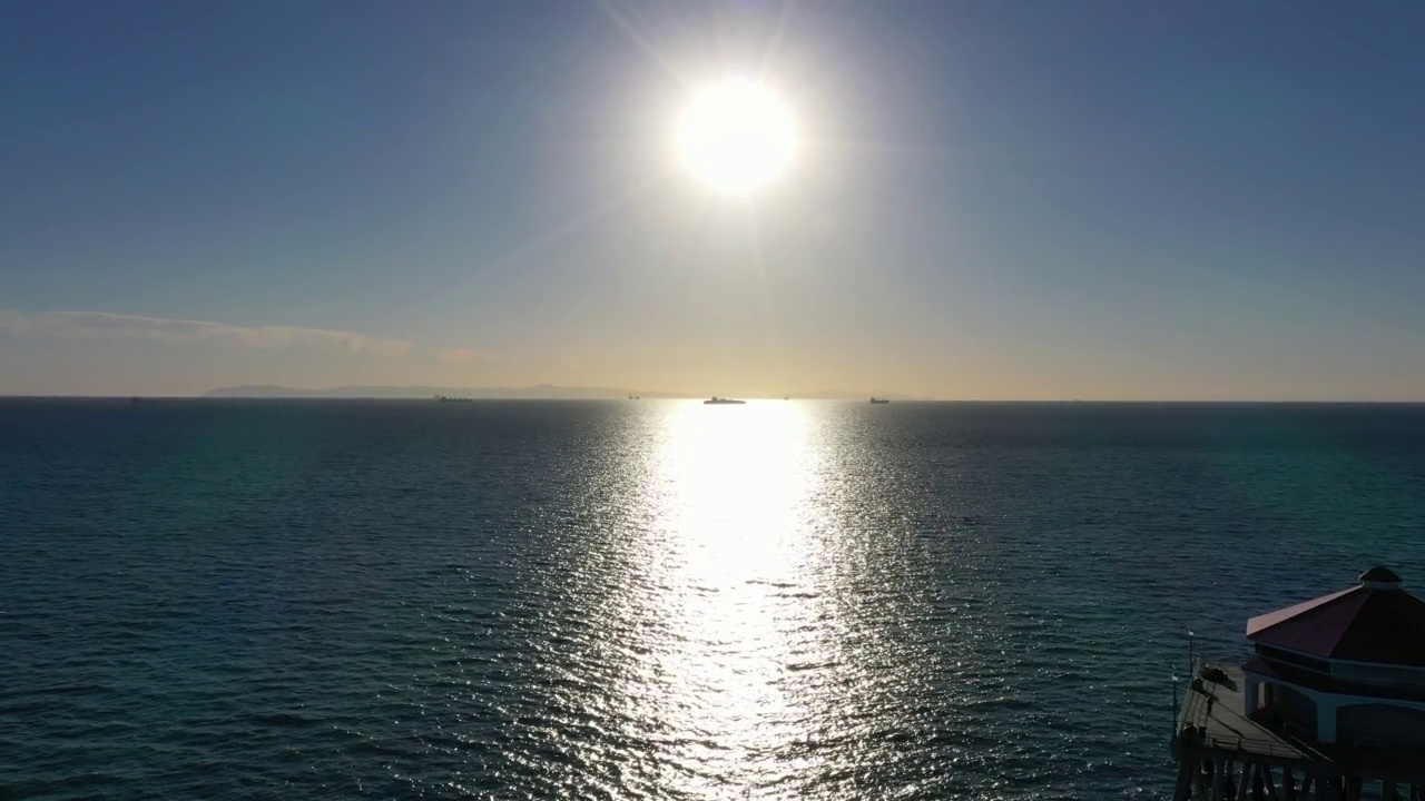 无人机在太平洋上空快速飞向地平线，太阳和船只在远处视频素材