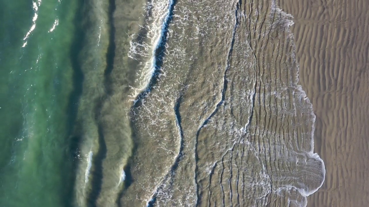 无人机与相机向下飞行平行海浪沿海滩海岸线视频素材