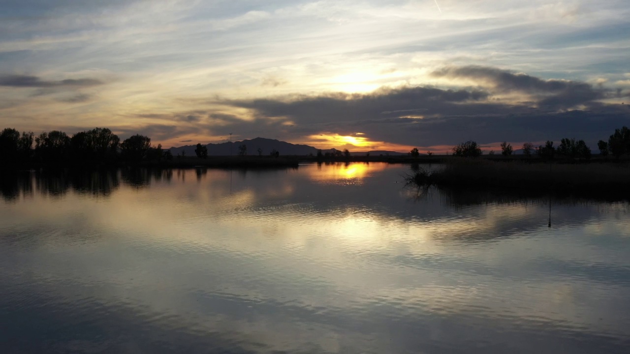 无人机在湖面上空飞行，朝着日落飞去，鸟儿在水上游泳视频素材