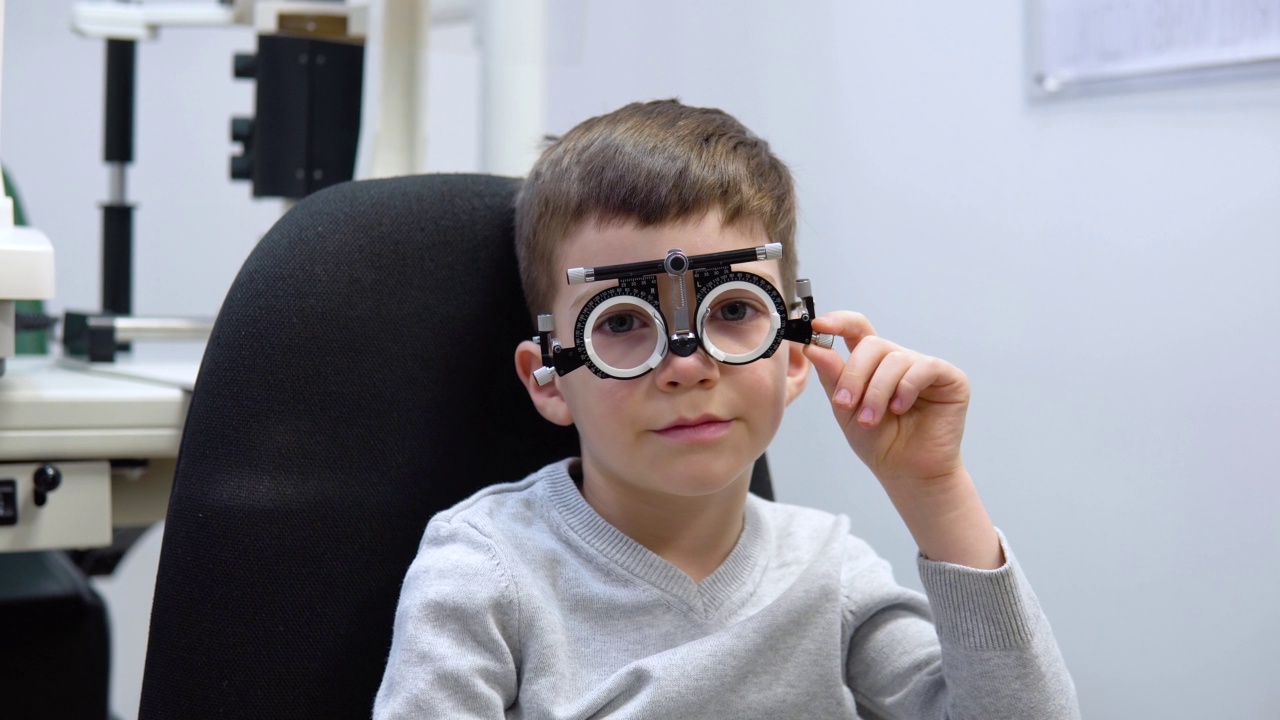 一个白人男孩在与眼科医生预约选择隐形眼镜的试验框架中视频素材