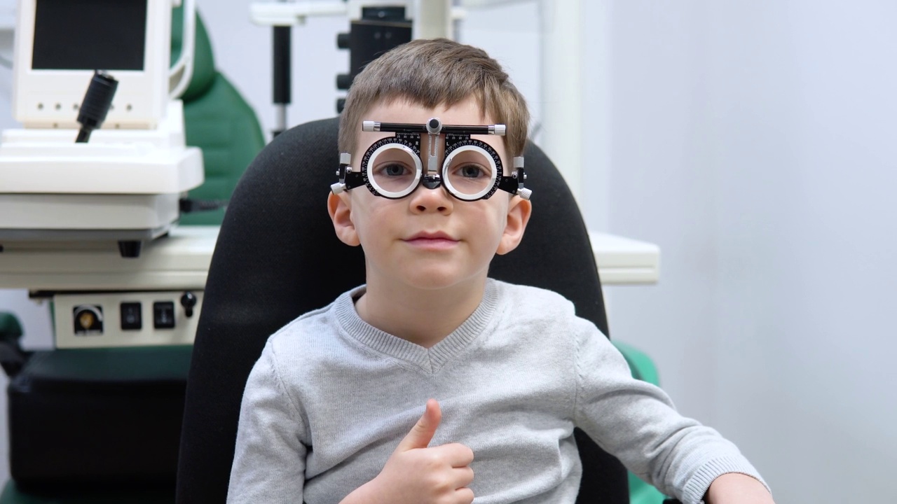 一个小男孩坐在光学商店的试镜架上挑选镜片视频素材