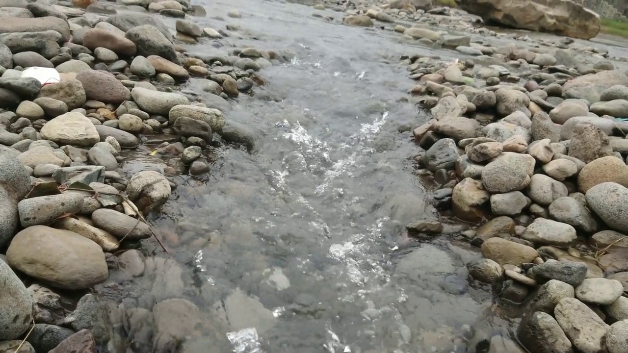河水在岩石间流动，摄影机移动拍摄视频素材