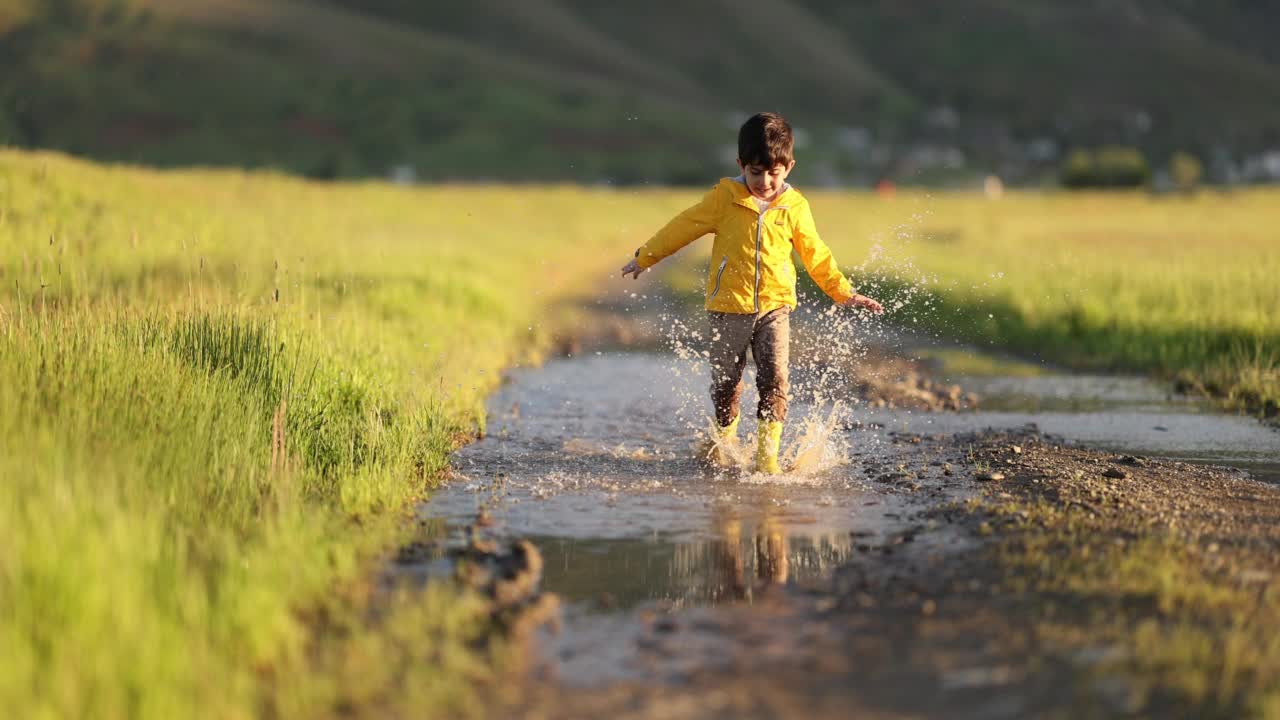 小男孩在泥泞的水坑里跳视频素材