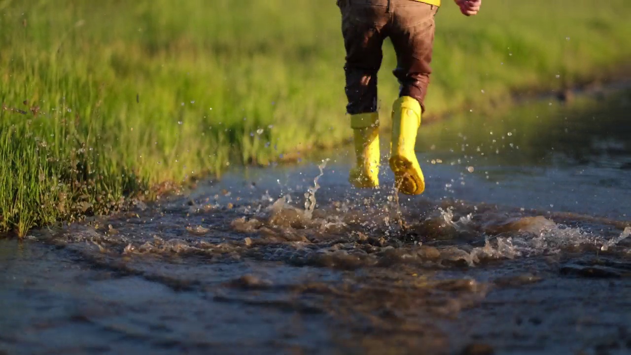 小男孩在泥泞的水坑里跳视频素材