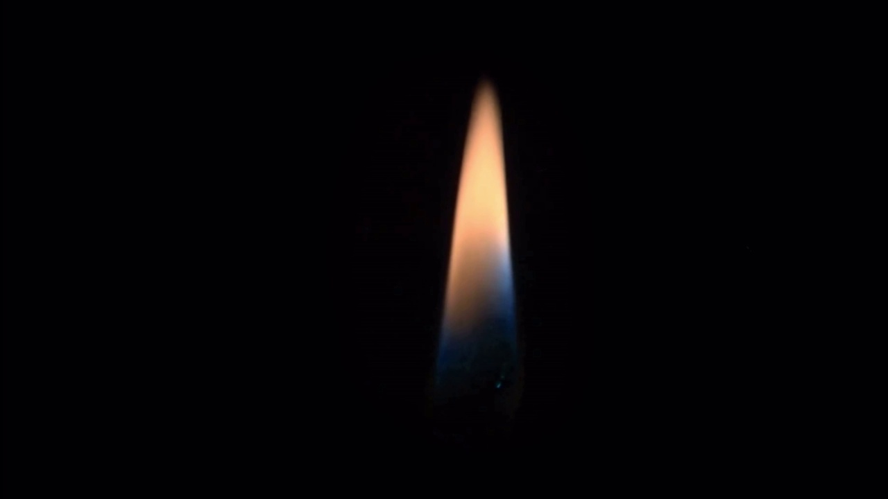 现实的橙色蜡烛火焰孤立在黑色背景。视频素材