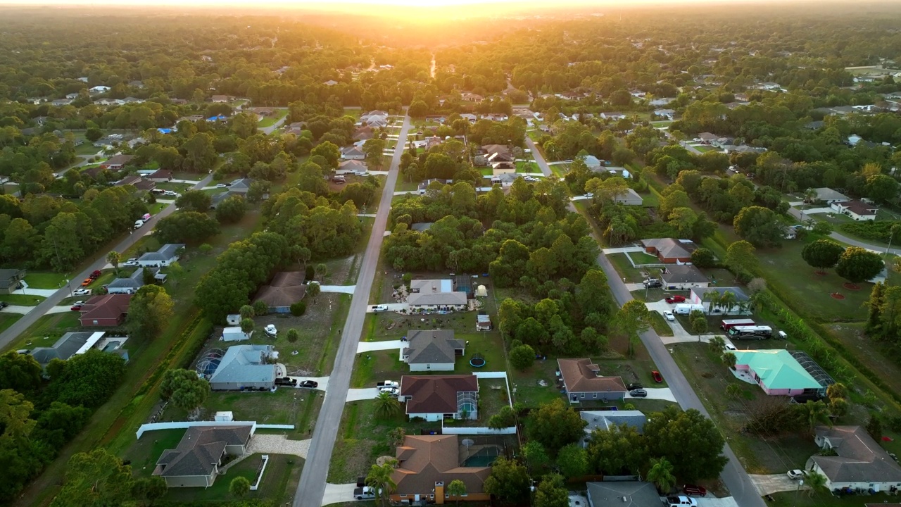 空中景观郊区私人住宅之间的绿色棕榈树在佛罗里达州宁静的农村地区在日落视频素材