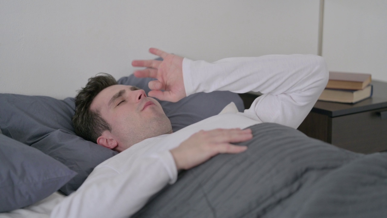 男子在床上睡觉时咳嗽视频素材