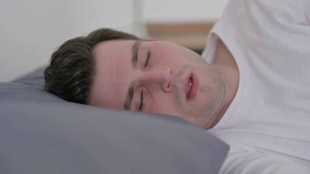 男子在床上睡觉时咳嗽，近距离观察视频素材
