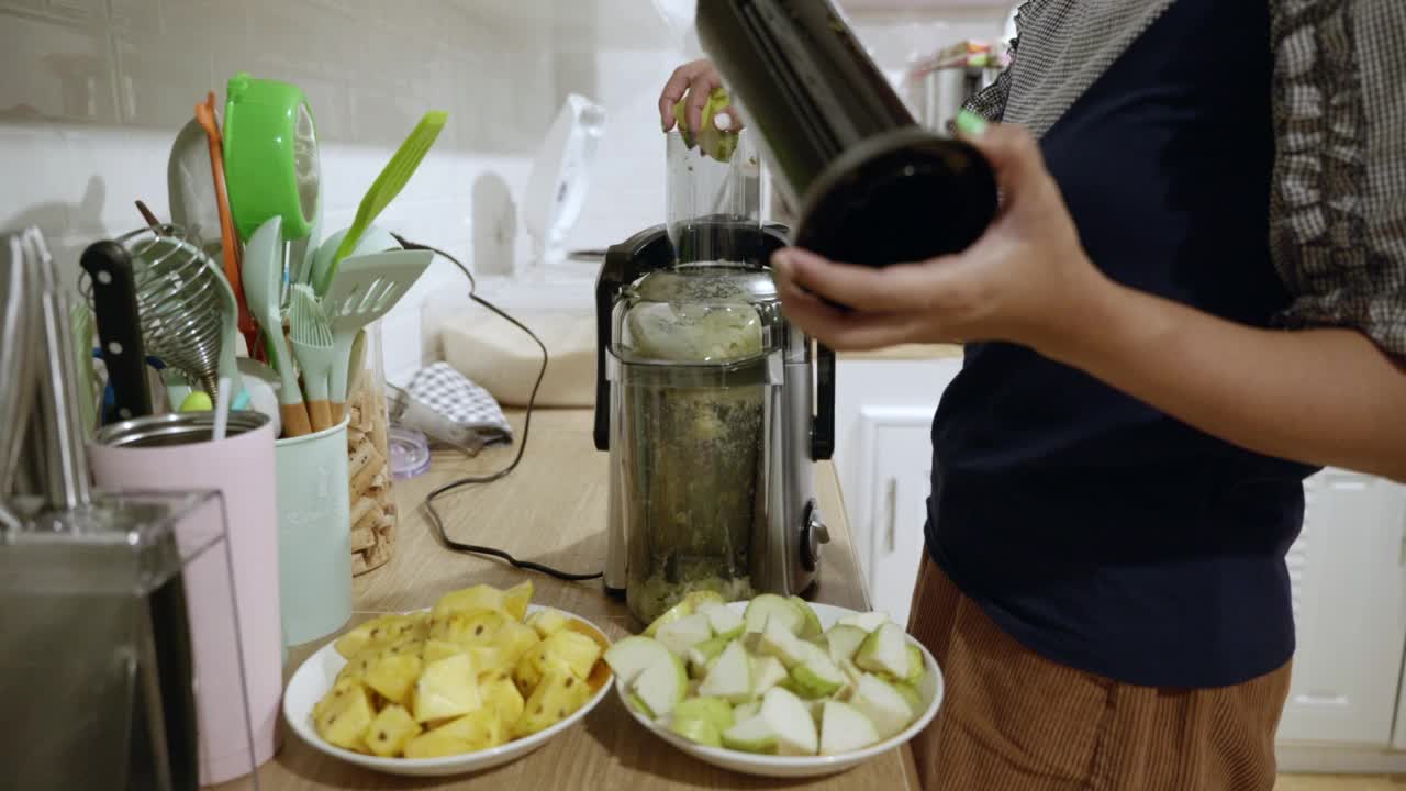 亚洲女人在厨房榨汁的场景，健康水视频素材