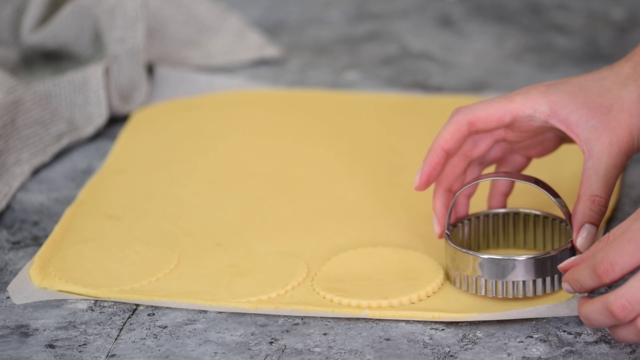女人用圆模具切出面团圈来做甜饼干。视频下载