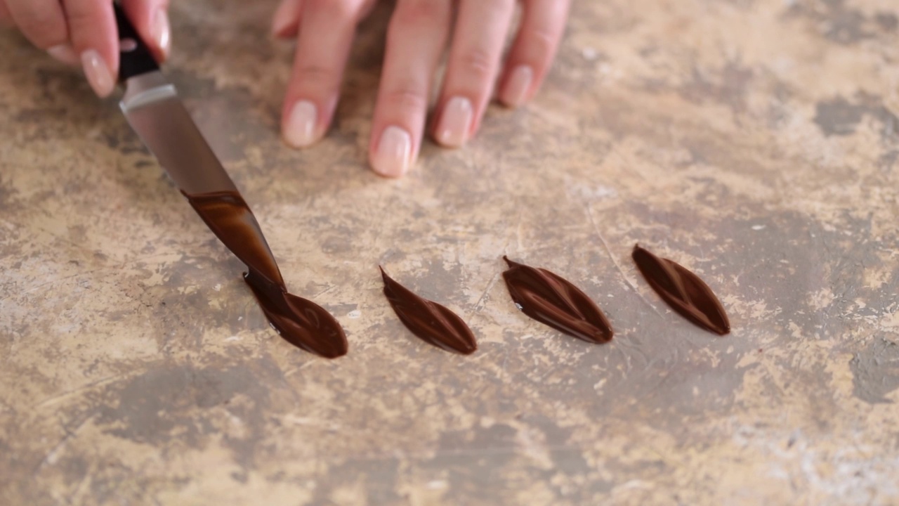 用黑巧克力做花瓣的女人的手。视频下载