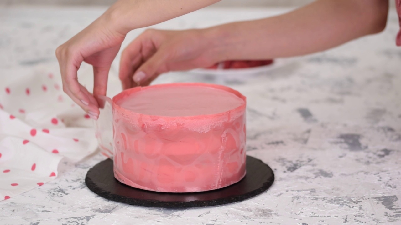 糕点师正在准备覆盆子慕斯蛋糕。用粉红色的巧克力装饰旁边的蛋糕。视频下载