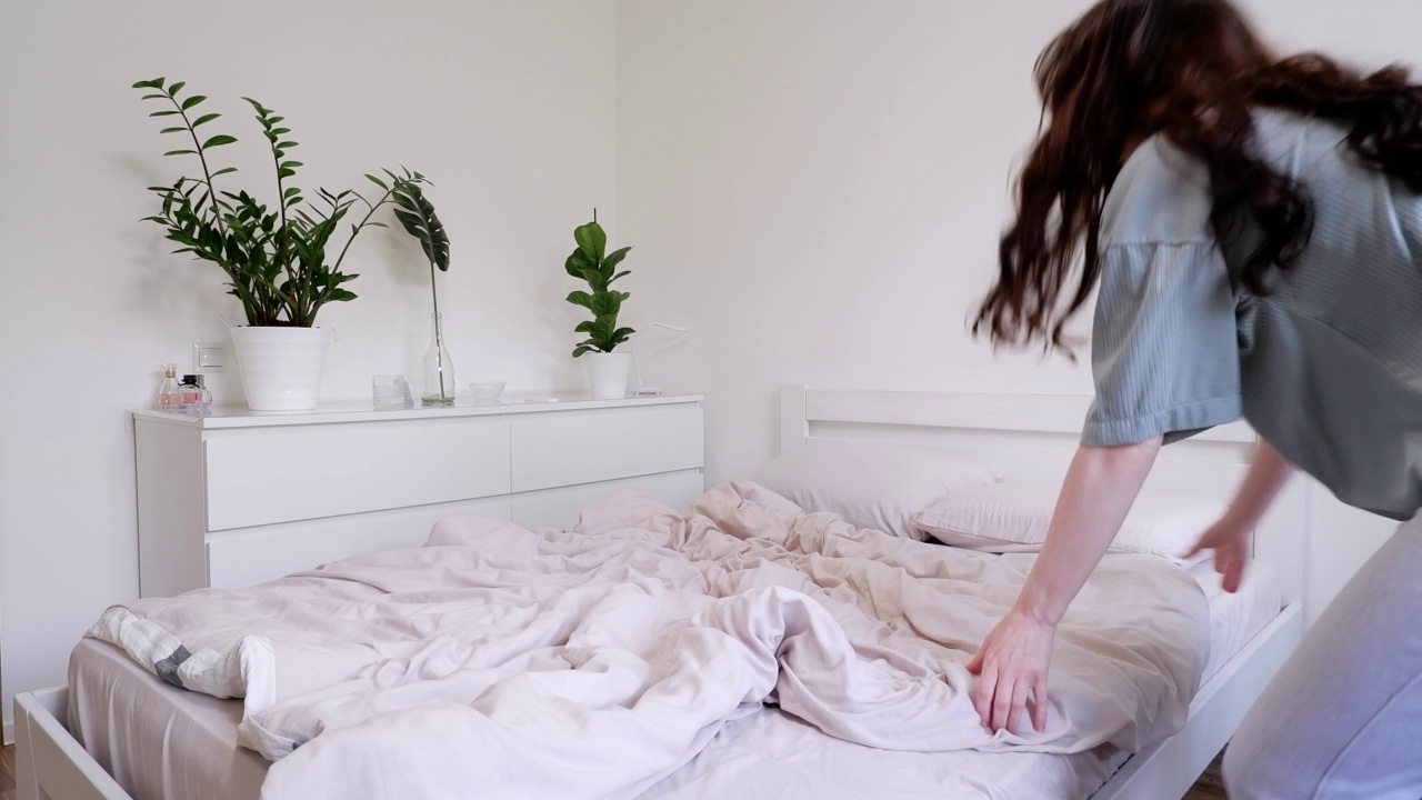 穿着睡衣的女人上床睡觉。现代风格的漂亮明亮的房间视频素材