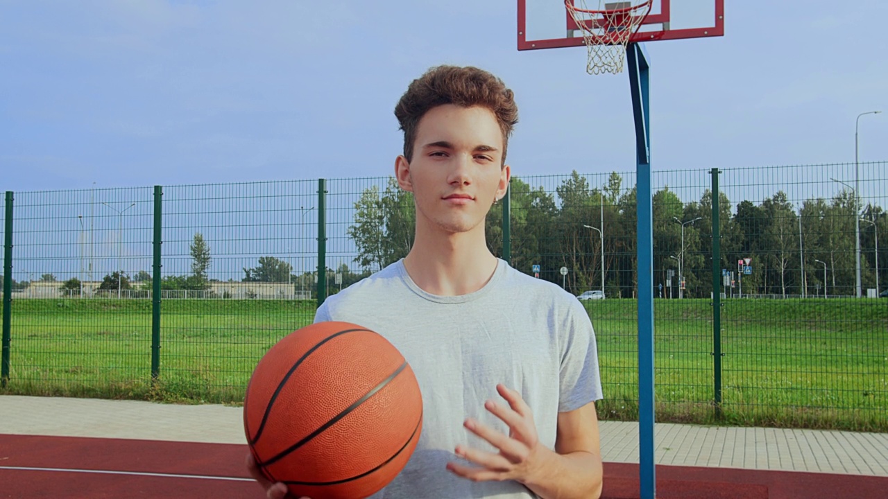 一个好看的男人的肖像在一个运动场上，手里拿着一个篮球，看着相机视频下载