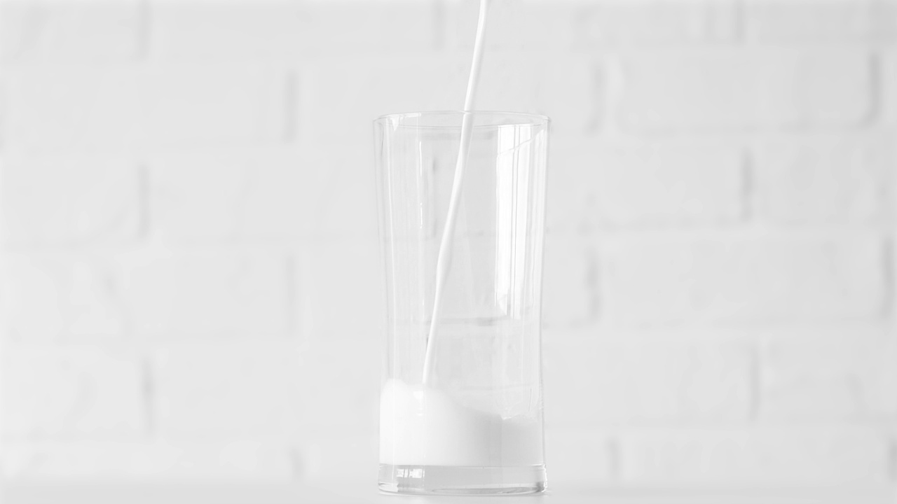 牛奶倒入玻璃上的白色背景特写视频素材